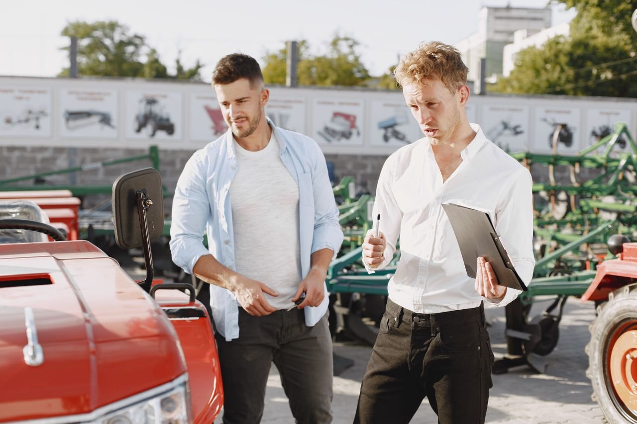 Two men engaging in a discussion about a tractor sale at an outdoor dealership.